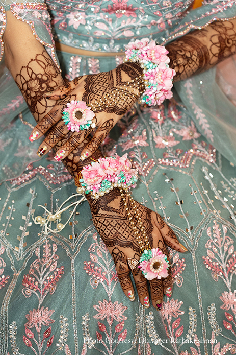 Bride in a teal blue and pink lehenga with floral jewelry for her mehendi
