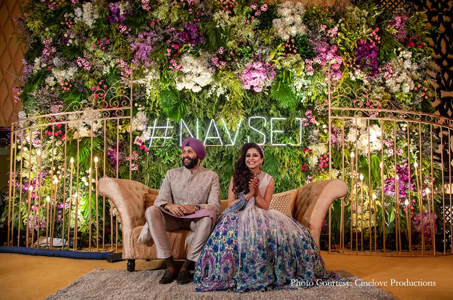 A lush foliage arch festooned with blooms in hues of pink and purple for the engagement decor