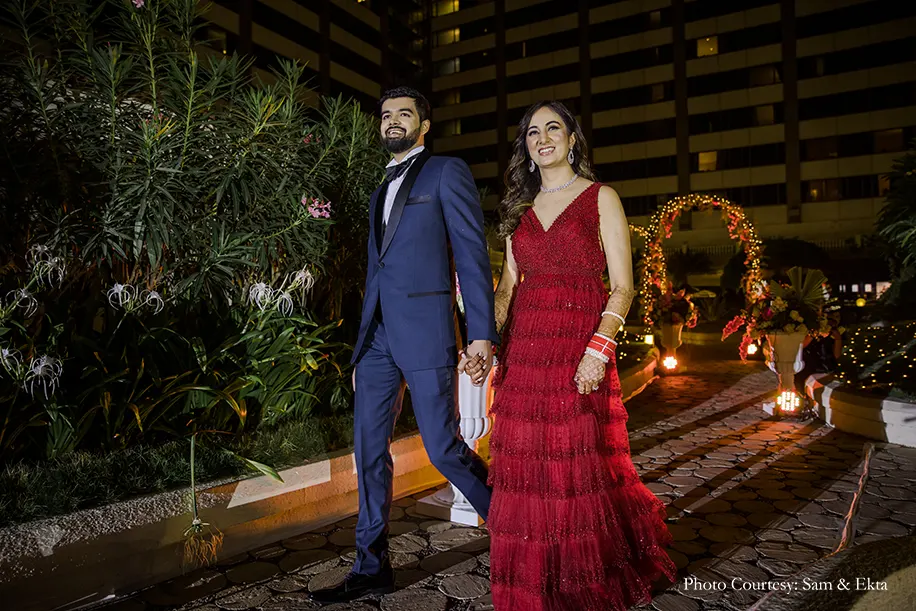 Bride wearing red shimmered gown and groom wearing blue tuxedo for the reception