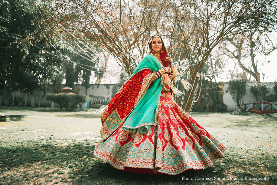 Bride Twirling in Rajasthani embroidery red and turquoise lehenga with statement jewelry