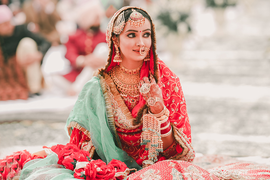 Bride wearing Rajasthani embroidery red and turquoise lehenga and groom in Off-white sherwani with an elaborate Kalgi and Mala at anand karaj