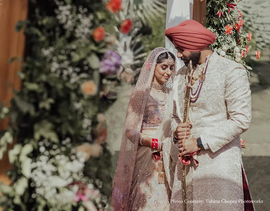 Bride in a Tarun Tahiliani ensemble with delicate floral motifs and appliqué-work, while the groom wearing embroidered blush pink sherwani