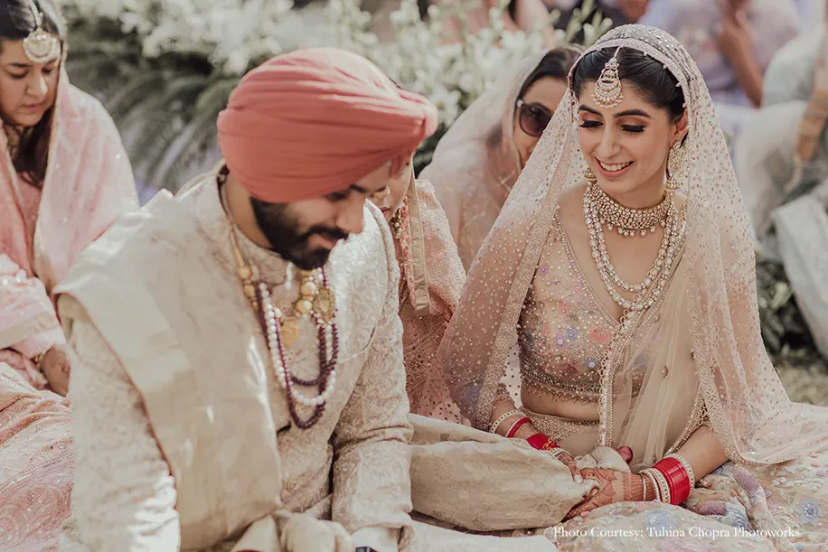 Bride in a Tarun Tahiliani ensemble with delicate floral motifs and appliqué-work, while the groom wearing embroidered blush pink sherwani