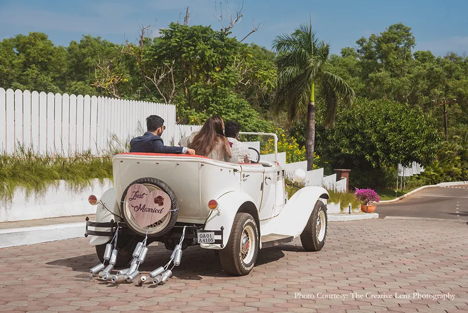 A vintage car, trailed by empty cans and a ‘Just Married’ board