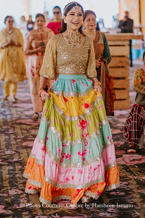 Bride wearing gold blouse and colorful mirror work lehenga for mehendi