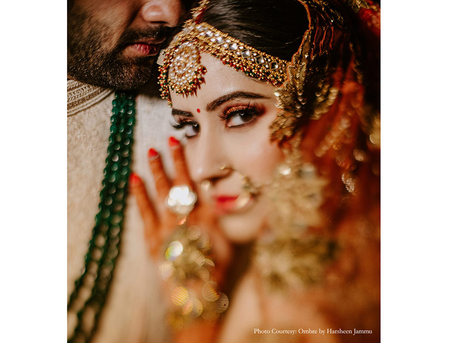 Bride in gold lehenga and groom in off-white sherwani for wedding
