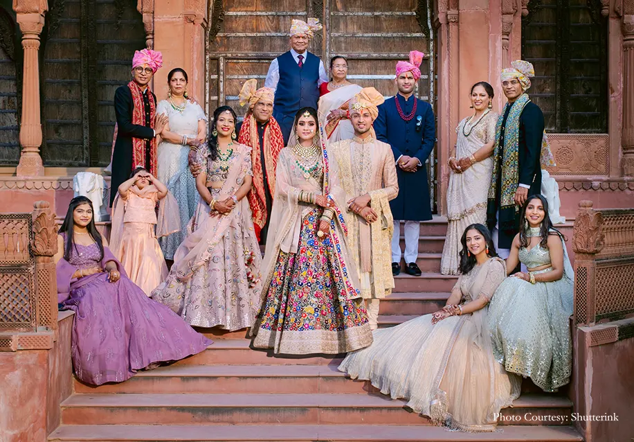 Bride in multicolored lehenga and Kundan jewelry and Groom in embroidered and heavily accessorized royal sherwan in family photo