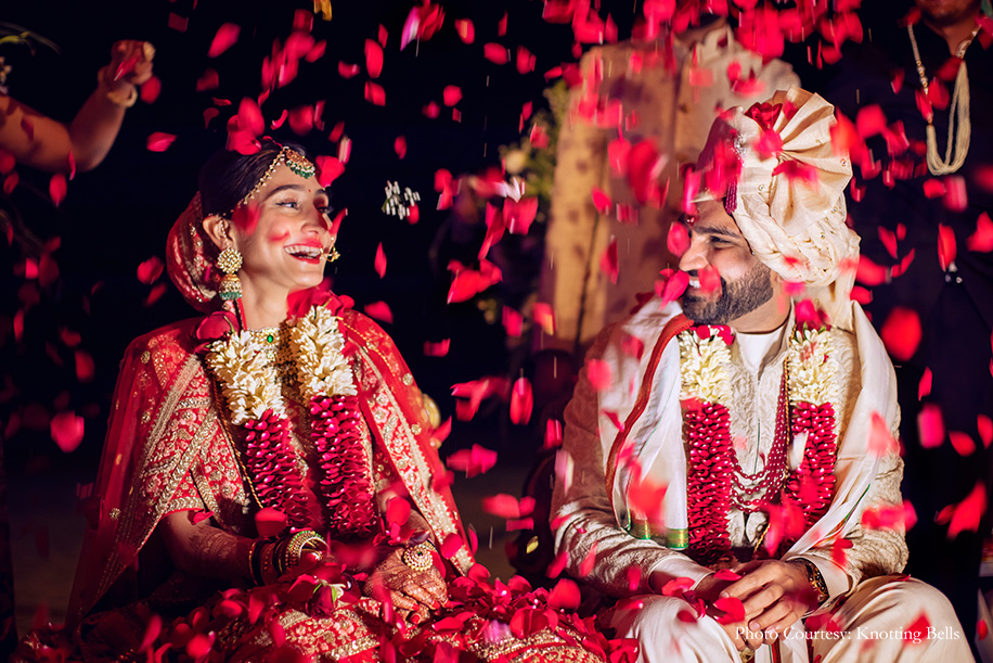 Bride wearing red Sabyasaachi lehenga and groom wearing off-white sherwani by Shantanu and Nikhil