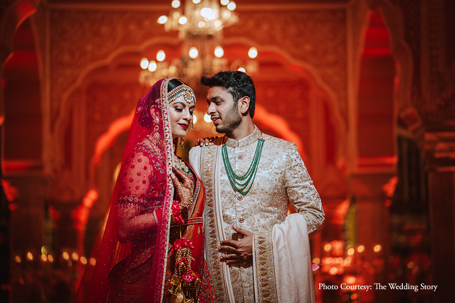 Bride in red lehenga by Tarun Tahiliani and groom in gold sherwani by Sabyasachi Mukherjee for the wedding at Jaipur