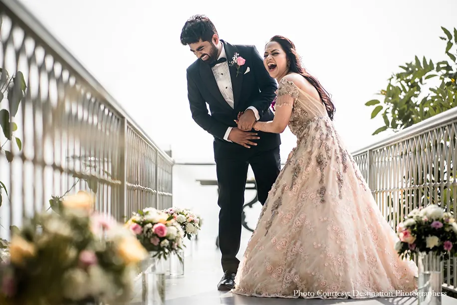 Bride wearing beige gown and groom wearing black tuxedo for the reception