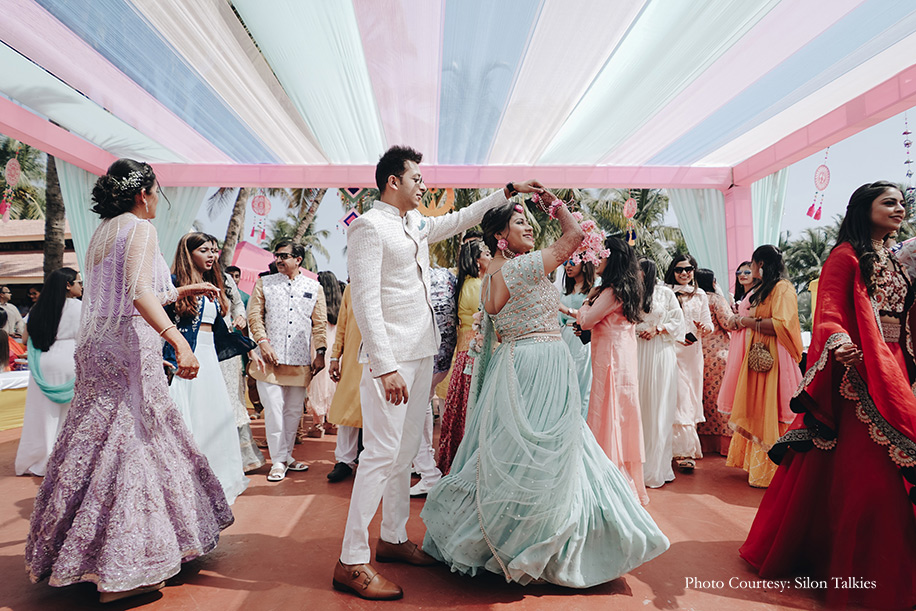 Groom donned a white bandhgala by Just Men while the bride was dressed in a sea green ‘Chamee and Palak’ lehenga with floral jewelry from ‘Floral by Shayoni’ with white and yellow floral decor for the mehendi function