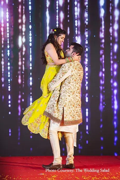 Bride wearing yellow lehenga and groom wearing beige and multi-colored embroidery bandh-gala